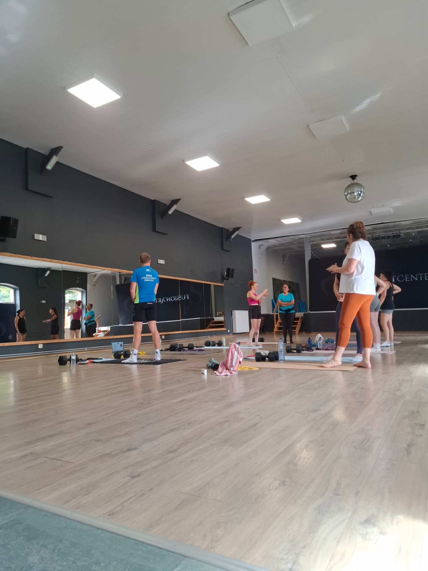 Cours collectif FORGE en cours dans la salle, tapis et haltères au sol